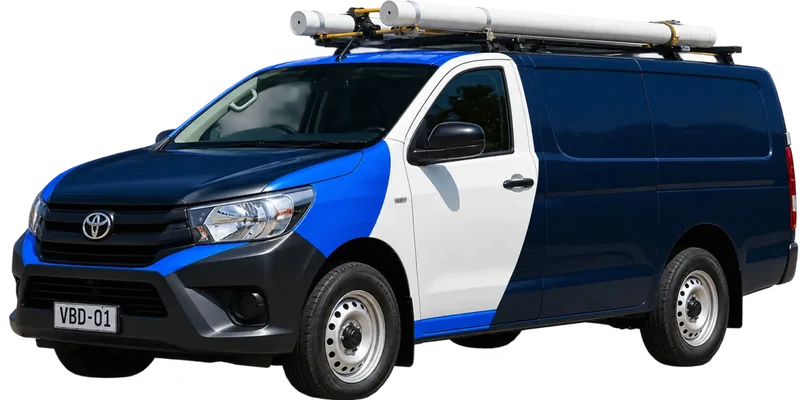 A licensed North Sydney plumbing van loaded with pipe on the roof rack